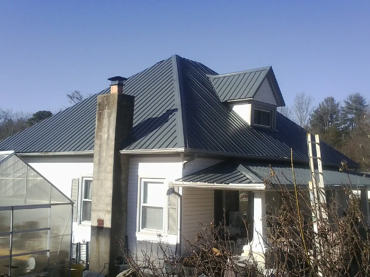 Dark blue standing seam metal roof on a white farmhouse with dormer — Slate & Tile Roof Repair by Roofing Brothers in Fairplay